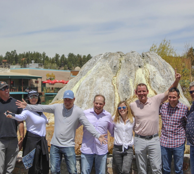 A group posing in front of a rock
