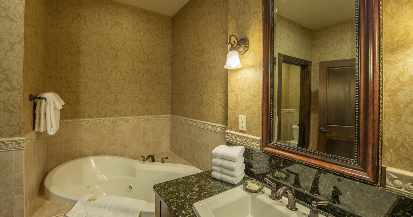 Condo Suite bathroom with marble bathroom countertop and a large mirror next to the bathtub