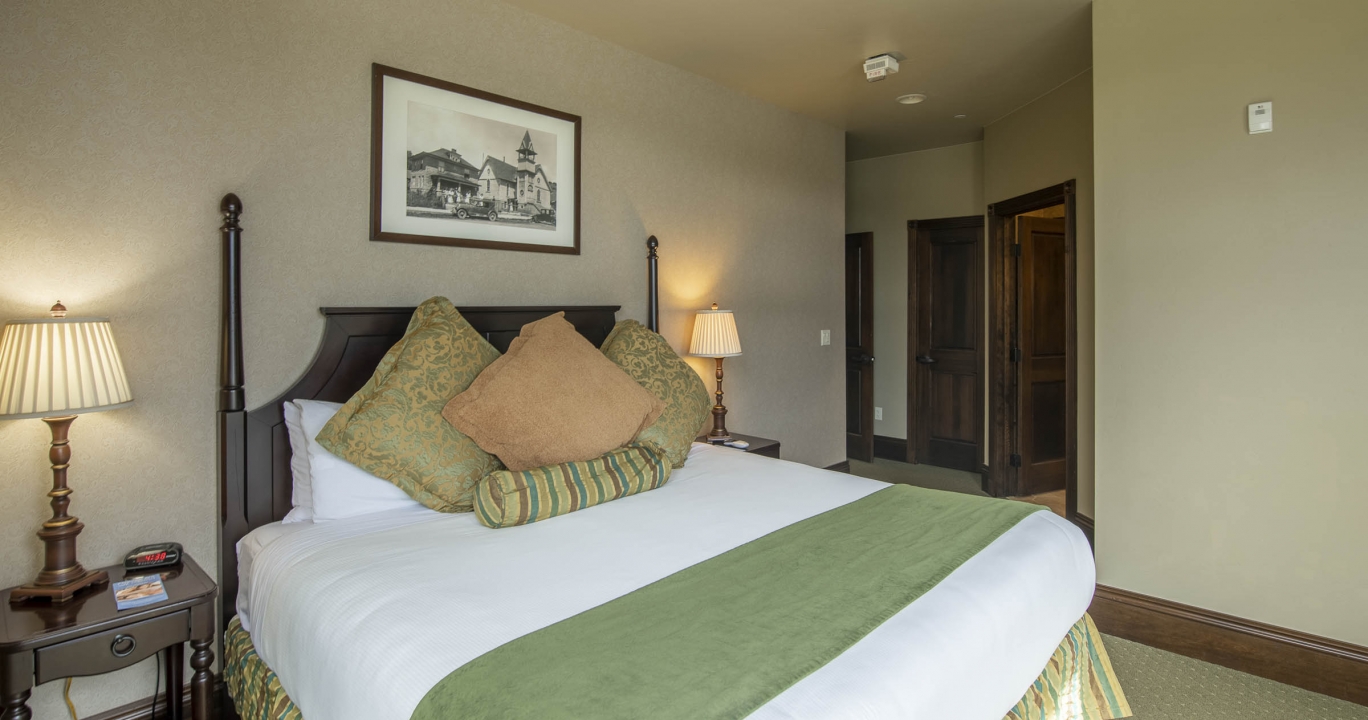 Spacious bed decorated with duvet, comforters and pillows with lamps on each side tables