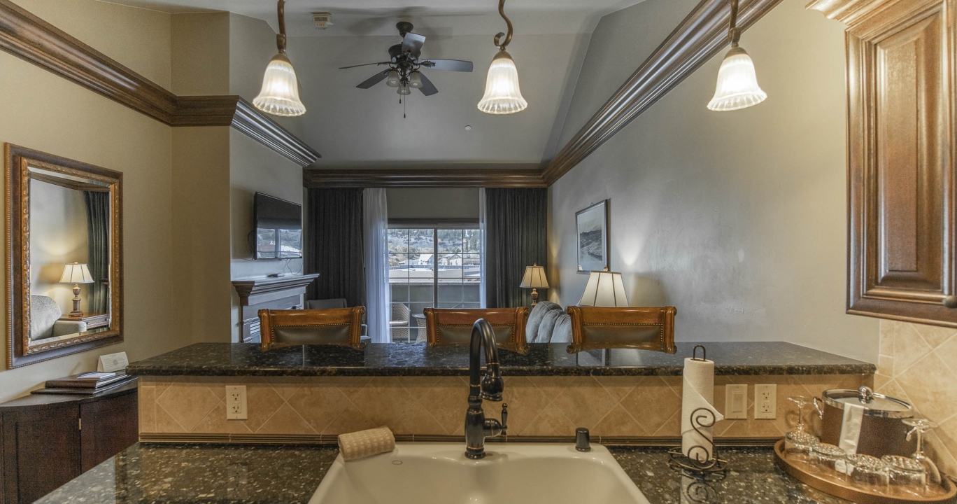 The kitchen sink counter overlooking the kitchen bar counter, chairs and the living room area