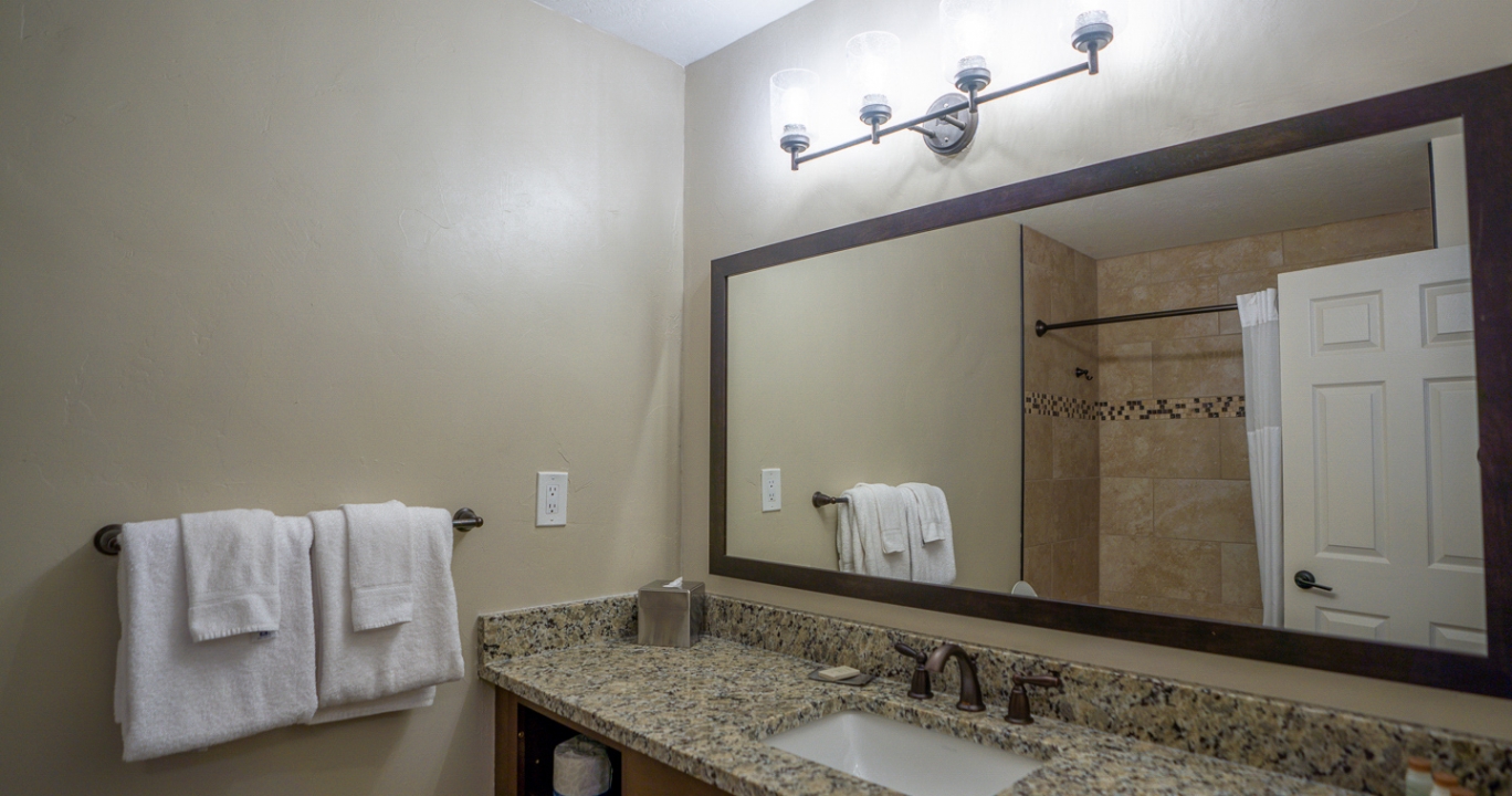 spacious marble countertop with a wide mirror and quadruple scone lights