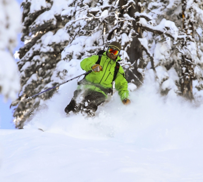 A man ice skiing wearing a green skiing gear