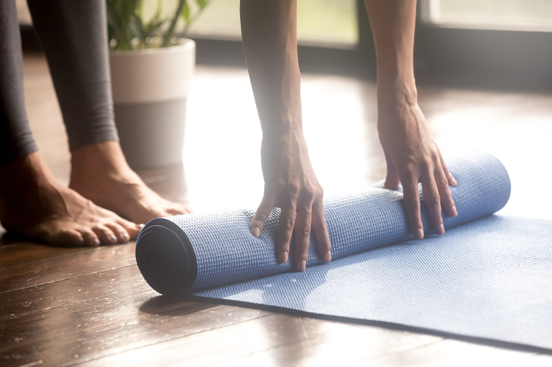 A pair of hand unrolling a yoga mat